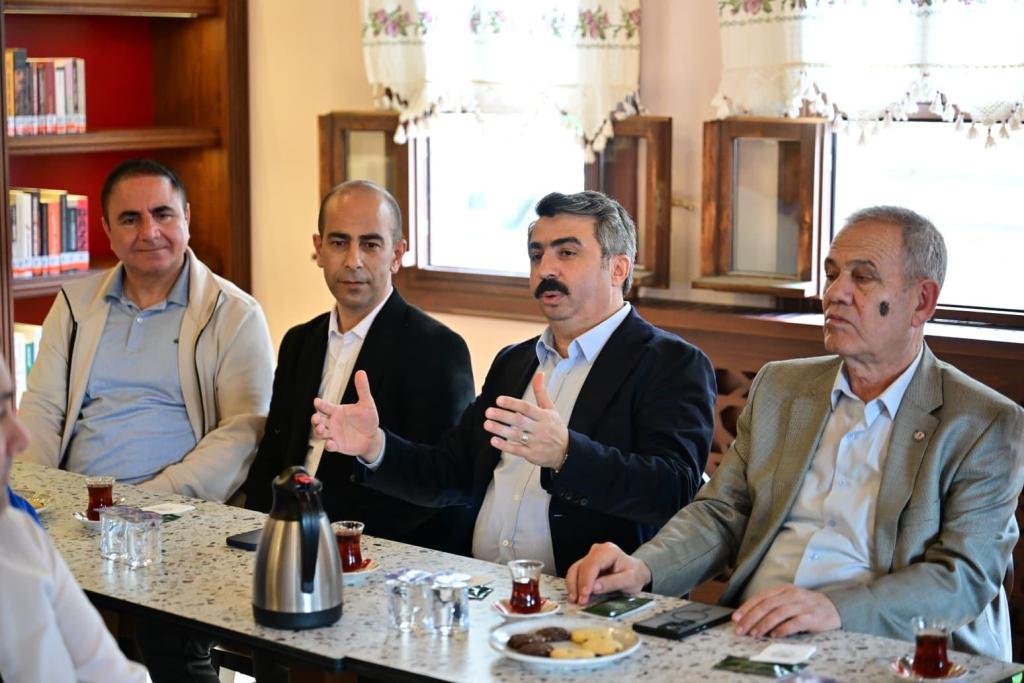 Bir kafede oturan dört adam, çay içerek tartışma yapıyor.